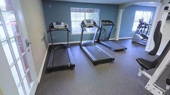 a gym with four treadmills and a window